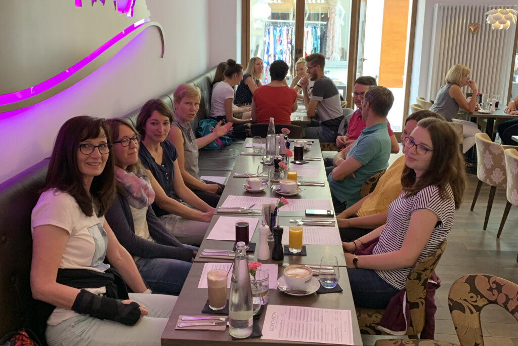 Mitarbeitende von Remde & Partner sitzen an einem langen Tisch in einem Restaurant und verbringen gemeinsam Zeit beim Essen.
